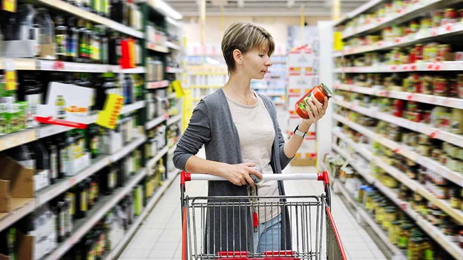 woman reading label on jar in supermarket